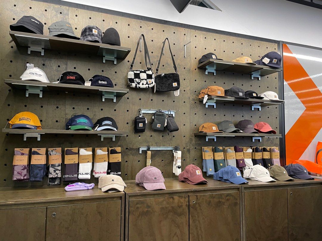 A range of Carhartt and other branded accessories such as hats and socks are placed neatly on a display wall.