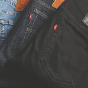 A stack of blue, dark, and black denim jeans folded on a dark surface.